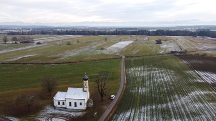 Raisting, Germany Bavaria - December 12, 2020: St. Johannes d. T&auml;ufe small white snowy roof wedding Chapel or Church sits in the country farm fields with winter trees. Near Munich and the Alps.