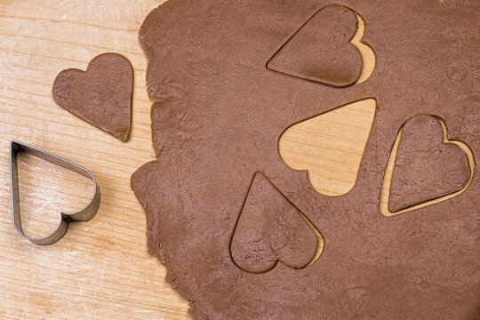Dough for cookies with heart shaped forms on wooden background.   Heart cookies for Valentine day, top view, flat lay image