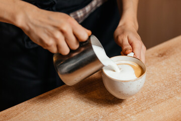 Fototapeta na wymiar Barista's hands whip milk foam to make cappuccino. High quality photo