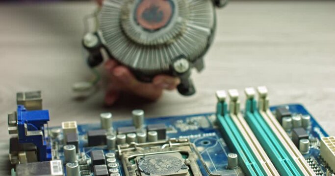 The wizard removes CPU cooling for diagnostics. Repair and maintenance of computer boards and the latest processors. Replacement of chip thermal paste. In Modern Electronic Manufacturing Factory