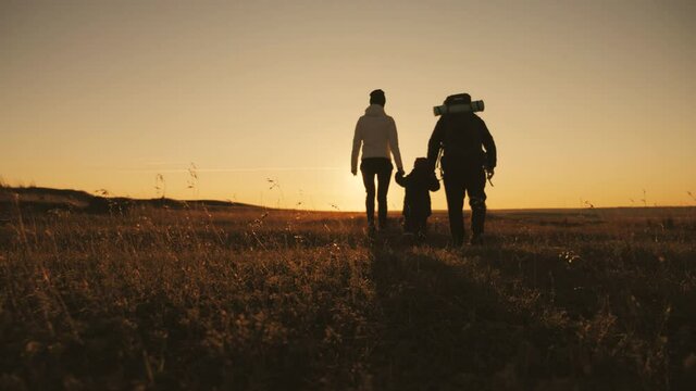 Silhouettes of father, mother and little son. Hiking backpackers trekking mountains summer. Young family on travel adventure vacation.