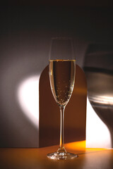 Glass of champagne in a round beam of light on a gray background with an arch.. Holiday and New Year concept. Copy space