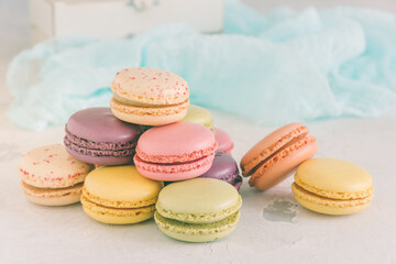Stacked pastel colored french macarons in front of a white wall