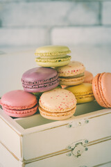 Pastel colored french macarons on a wooden vintage box, vertical