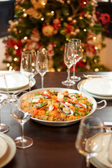 Spanish dinner table with assortment of dishes. paella, octopus, whole fish, sangría and wine. Dressed for christmas