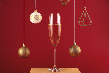 Two glassess of champagne on a stand on a red background with christmas balls and decorations. Holiday and New Year concept.