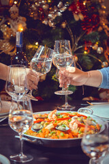 People sharing Spanish dinner table with assortment of dishes. paella, octopus, whole fish, sangría and wine. Dressed for christmas