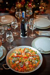 Spanish dinner table with assortment of dishes. paella, octopus, whole fish, sangría and wine. Dressed for christmas