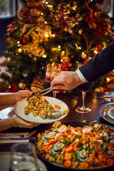 Spanish dinner table with assortment of dishes. paella, octopus, whole fish, sangría and wine. Dressed for christmas