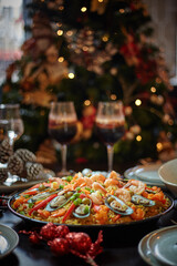 Spanish dinner table with assortment of dishes. paella, octopus, whole fish, sangría and wine. Dressed for christmas