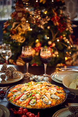 Spanish dinner table with assortment of dishes. paella, octopus, whole fish, sangría and wine. Dressed for christmas