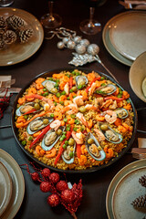Spanish dinner table with assortment of dishes. paella, octopus, whole fish, sangría and wine. Dressed for christmas