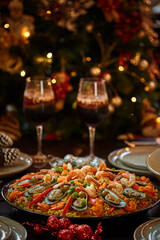 Spanish dinner table with assortment of dishes. paella, octopus, whole fish, sangría and wine. Dressed for christmas