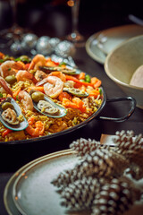 Spanish dinner table with assortment of dishes. paella, octopus, whole fish, sangría and wine. Dressed for christmas