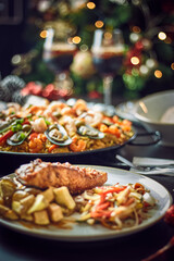 Spanish dinner table with assortment of dishes. paella, octopus, whole fish, sangría and wine. Dressed for christmas