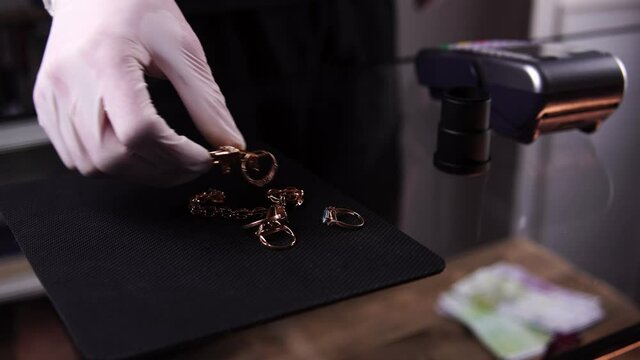 Woman sells golden jewel in pawnshop to earn money for them. Man is watching at rings, chain and brooche and counts euros. Theme of business and professional occupation. Buying of precious metals.