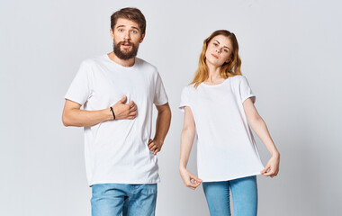 Portrait of a man and a woman in identical t-shirts teenager jeans light background