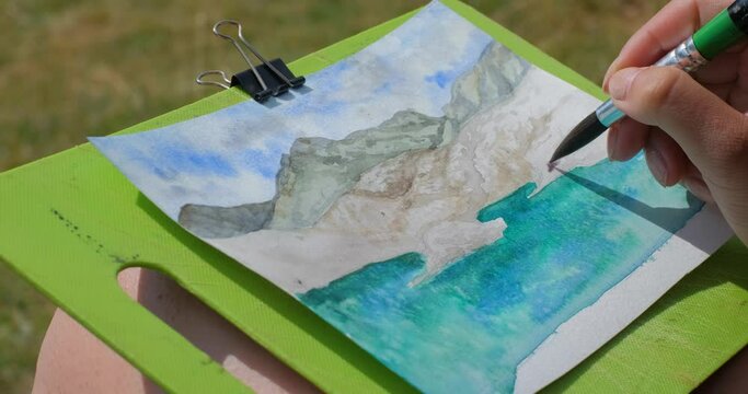 Young woman artist paint landscape with mountains outdoors