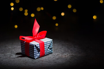 A box with a gift on a dark background. Red tape.