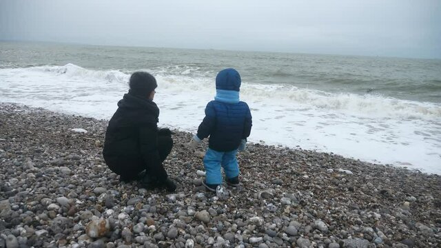 CTS1 Child Throwing Stone in Stormy Sea. Waves Crashing on Pebble Beach. Atlantic Ocean. Grey Overcast Sky. English Channel. France Europe. 2x Slow motion 60 fps 4K