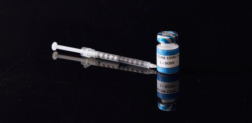 Covid-19 Vaccine bottle and syringe for injection on a black background.   