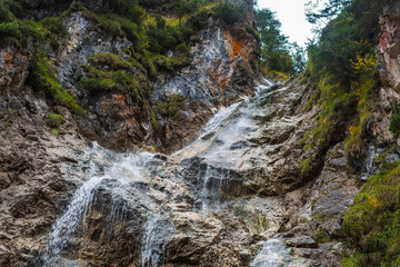 steep rocks with fine waterfall and green plants