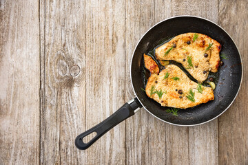 Roast Turkey in a frying pan on a wooden table.