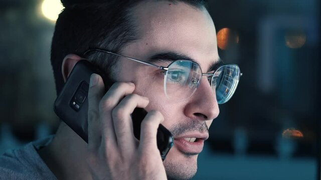 Late at night talking on the phone in front of a computer monitor.