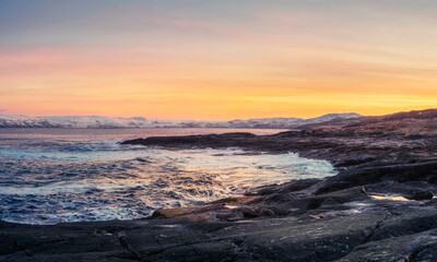 A rock cliff with a tidal shoreline. Wonderful panoramic mountain landscape on the Barents sea.