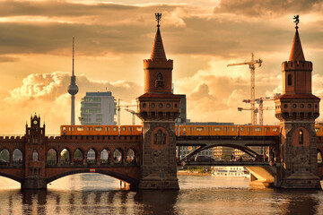 Obraz na płótnie Canvas Old bridge with a train across the river against sunset sky in Berlin, Germany