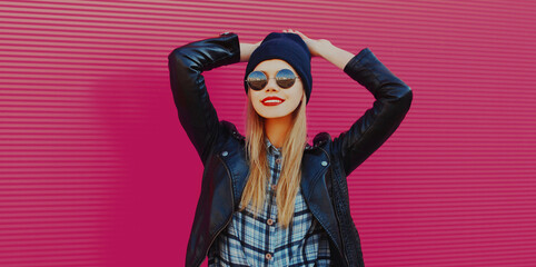 Portrait of stylish beautiful blonde woman in black rock style over a pink background