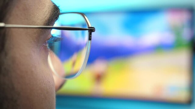Playing a video game on a computer monitor. Reflection of the game on eyeglasses. Closeup
