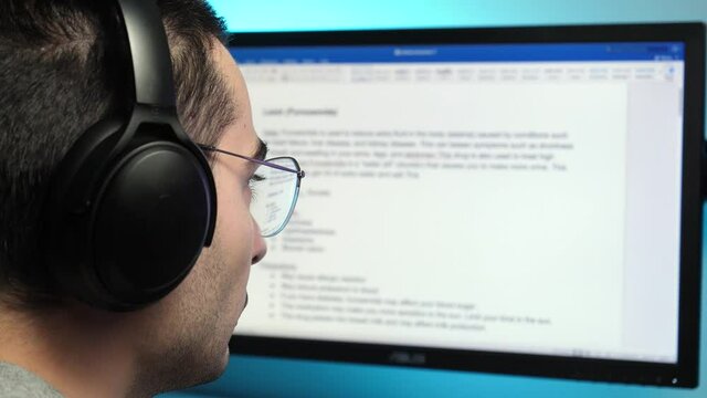 Writing a text in a text editor on a computer monitor wearing headphones at home. freelancer, student concept shot.