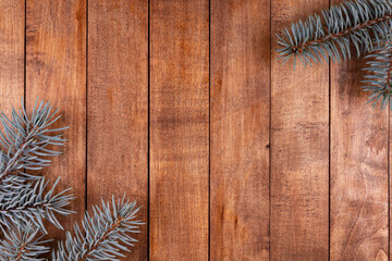 two branches of blue spruce lie on a brown wooden surface. one on the other