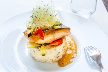 Plate of salmon with rice and a fork with sprouted seeds on it
