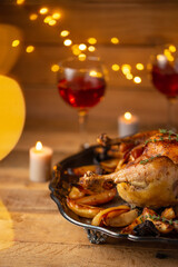 Close-up view appetizing baked turkey with potato on wine glasses and candles background. Concept of festive Christmas dinner.