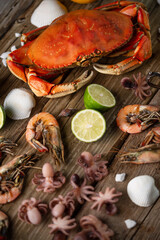 Top view of assorted seafood served with spices on rustic wooden background. Cooked crab, shrimps and baby octopuses for dinner. Seafood concept.