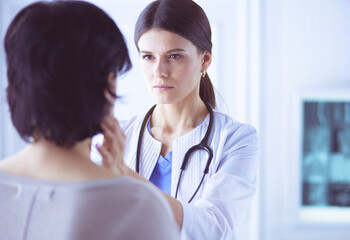 A serious female doctor examining a patient's lymph nodes