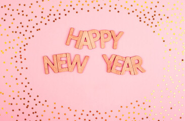 Beautiful Happy New Year lettering in wooden letters on a pink background with gold stars.