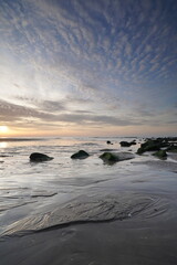 Fototapeta na wymiar Sunset on the beach. Seascape with an impressive blue, orange sky. Green rocks in foreground