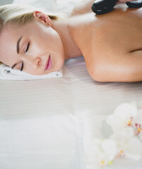 Fototapeta na wymiar Young woman in spa salon, getting stones massage