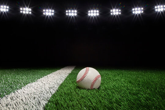 Baseball on a field with stripe and black background under lights