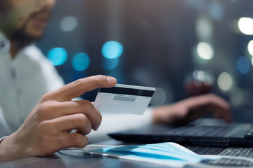 Young Black African American businessman paying with credit card online making orders via Internet. Successful black male holding plastic card making transaction using mobile banking application