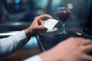 Young Black African American businessman paying with credit card online making orders via Internet. Successful black male holding plastic card making transaction using mobile banking application