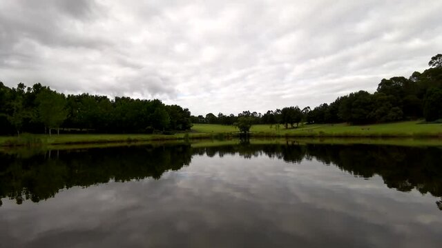 Beautiful time lapse video of a pond with stunning reflections of trees and slow moving clouds on water, Fagan Park, Dural, Sydney, New South Wales, Australia

