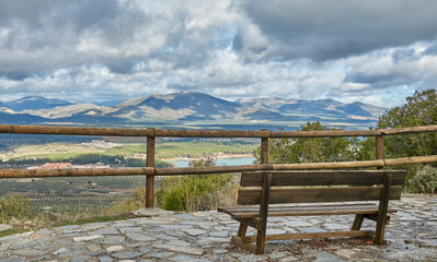 Fototapeta na wymiar Panoramic view of the Cubillas reservoir, mountains and fields from a viewpoint with a wooden bench in Sierra Elvira (Granada)