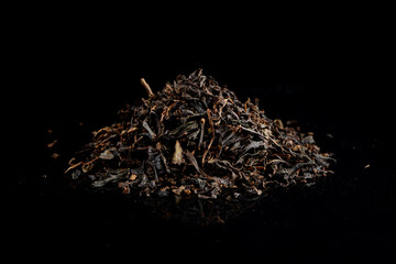 dry black tea leaves, pile of black tea isolated on a black background