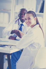 Two happy smiling young medical people handshaking at office. Doctors. Teamwork