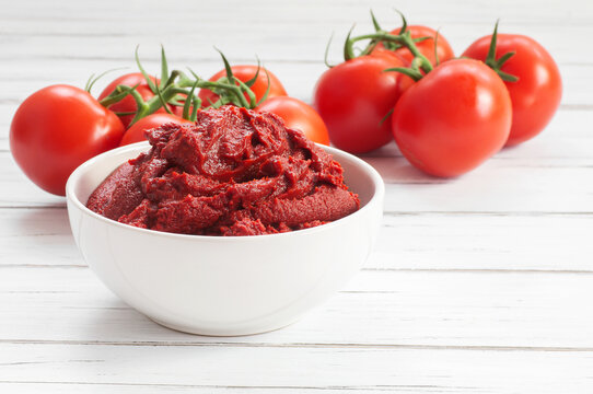 Traditional turkish tomato paste in bowl or spoon with fresh tomatoes on wooden table, homemade healthy food