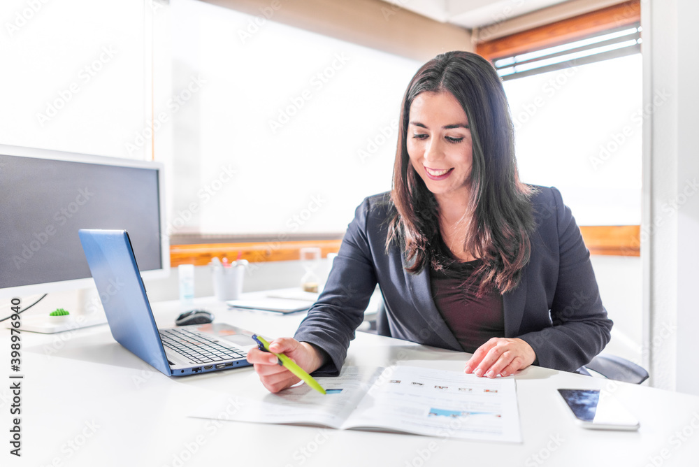 Wall mural woman in office with blue laptop in white office with lots of light and large veins working at desk